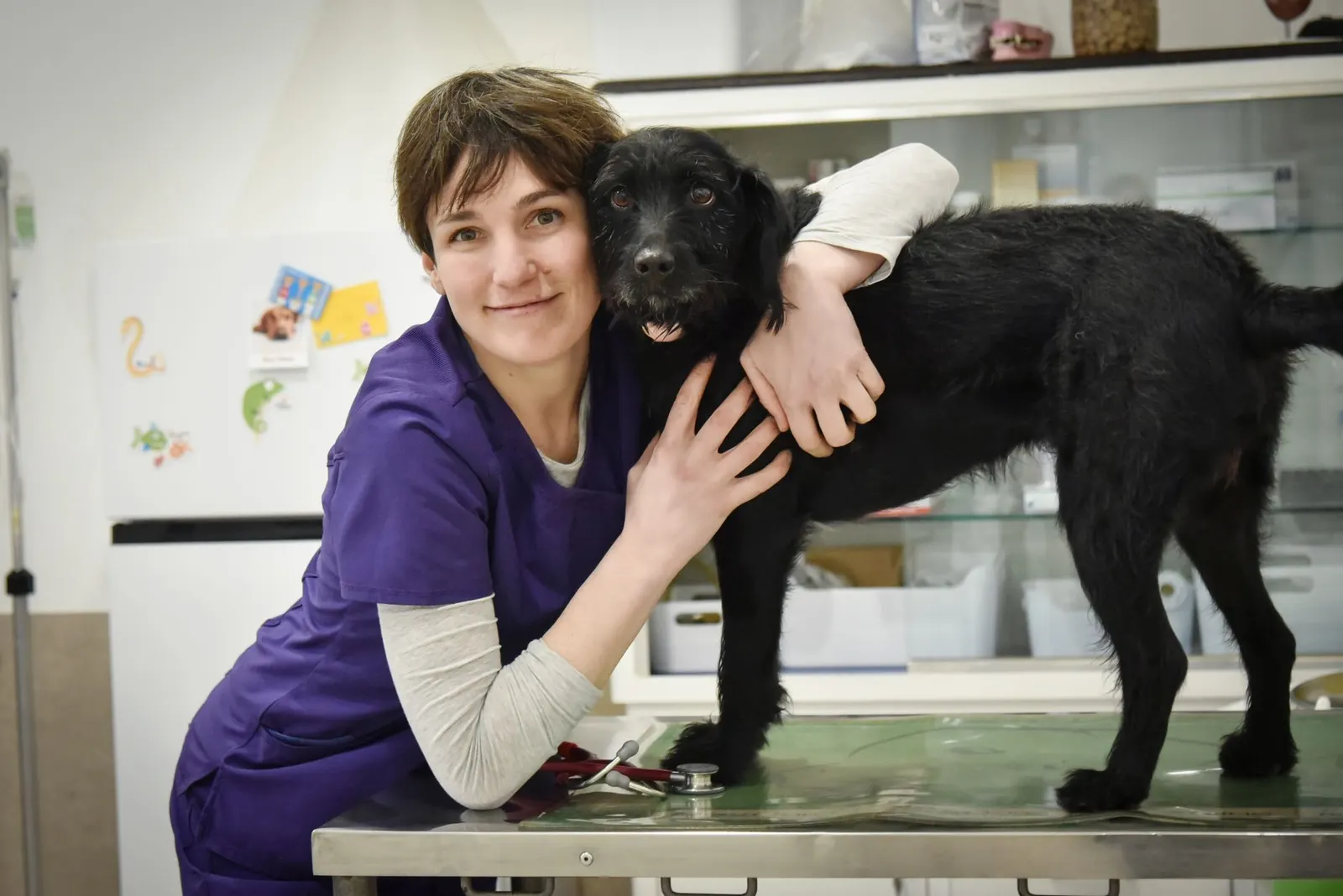 Una veterinaria abbraccia un grande cane nero